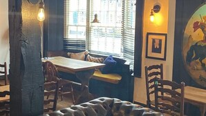 A cozy interior with a leather sofa, wooden dining table, and rustic decor. - George and Dragon Hotel (High Wycombe)