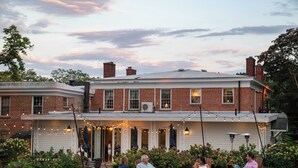 A brick house with a porch, outdoor seating, and string lights. - Cromwell Manor Inn (Cornwall)