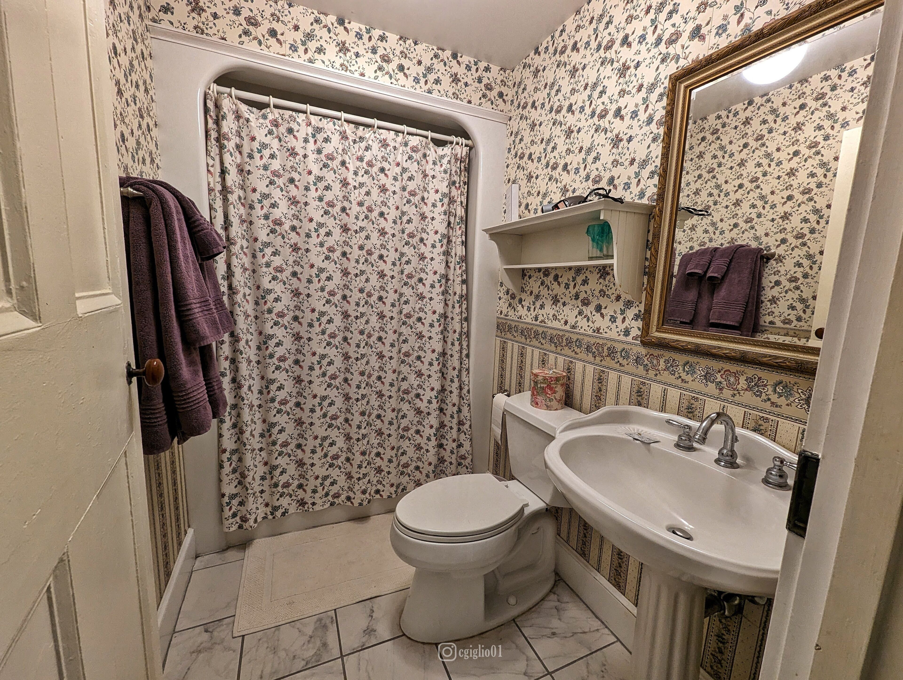 A bathroom with a toilet, sink, and shower curtain.