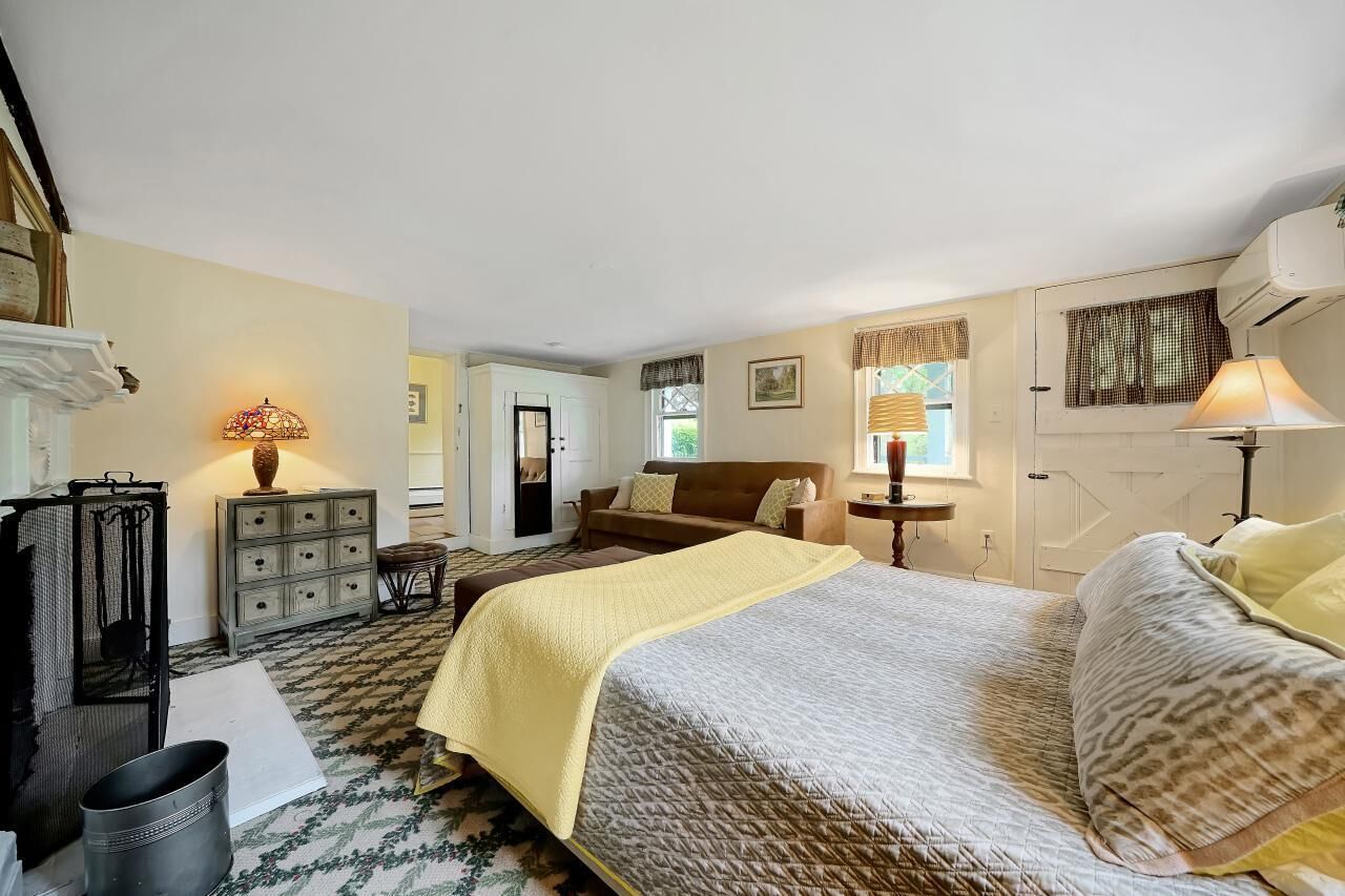 A bedroom with a bed, a dresser, a chair, a lamp, and a window.