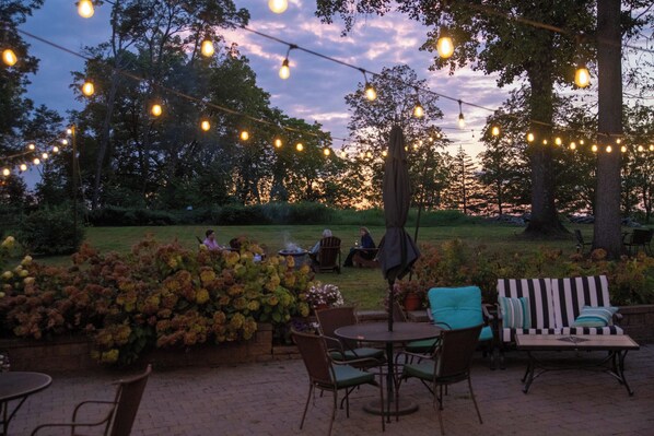 An outdoor patio area with string lights, seating, and a view of the garden.