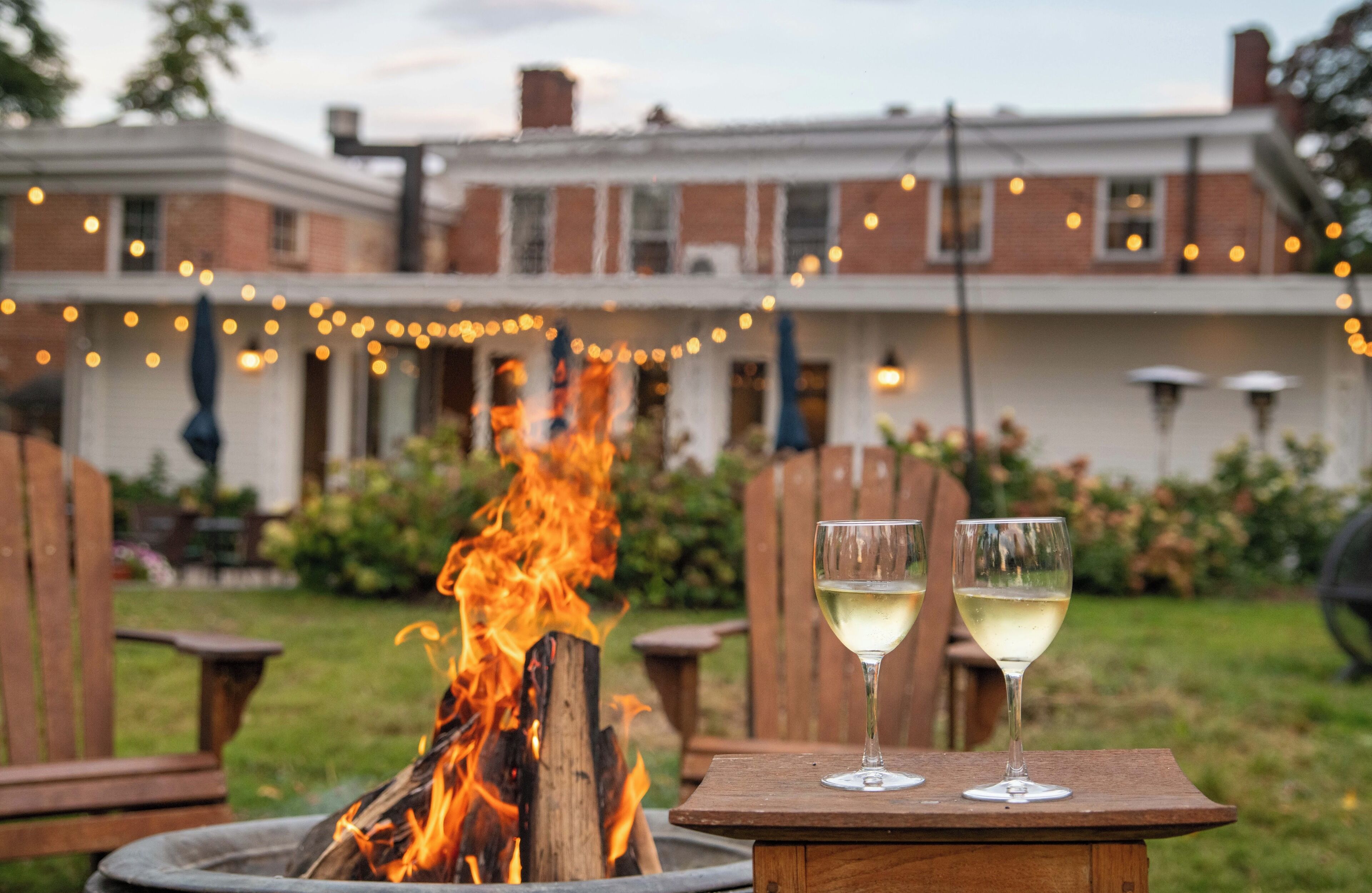 Un foyer avec deux verres de vin blanc, une table en bois et un bâtiment en briques en arrière-plan.