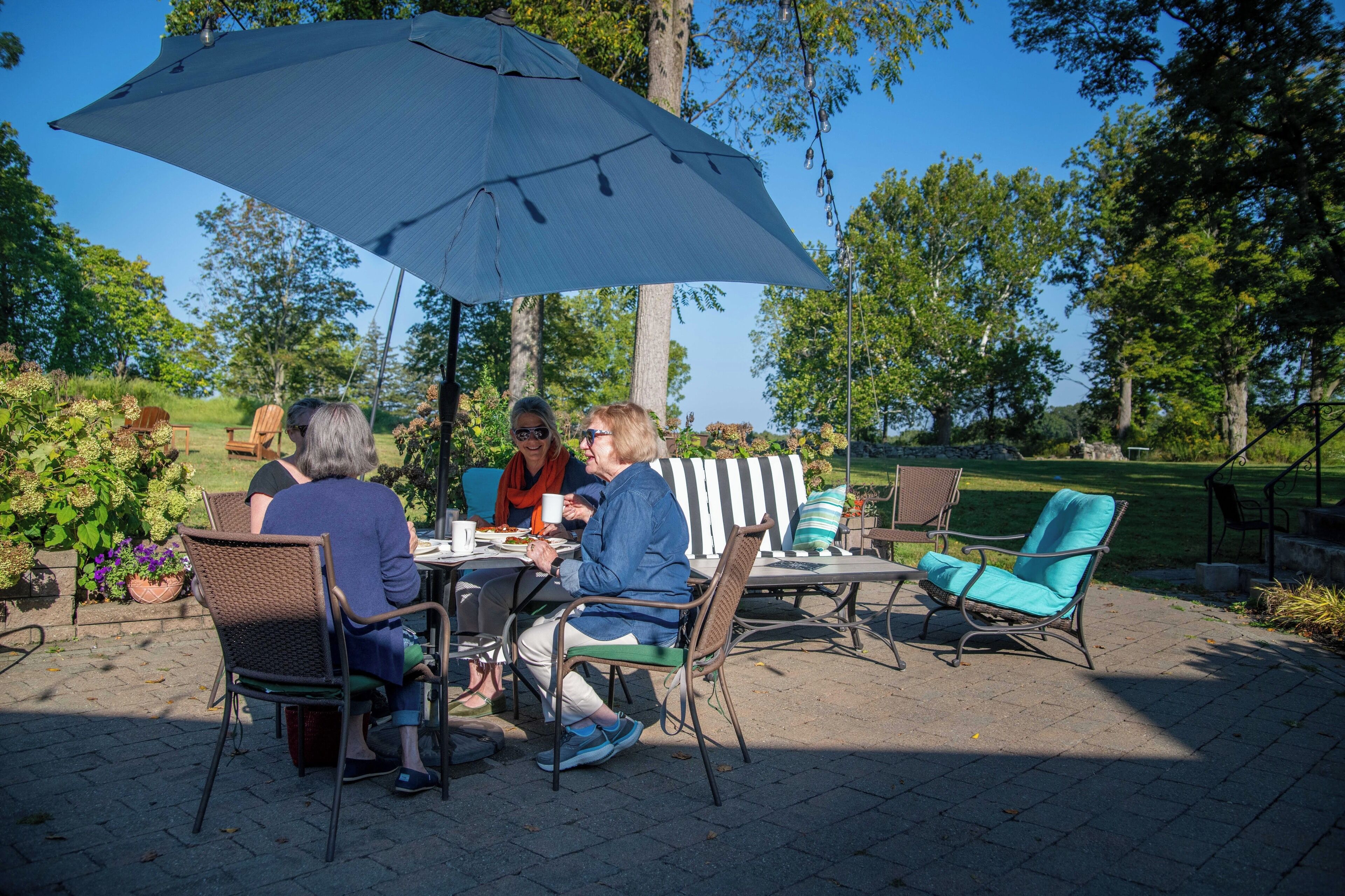 A patio with outdoor furniture, including chairs and a table, under a large umbrella.