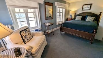 A bedroom with a bed, a sofa, a small table, and a lamp.