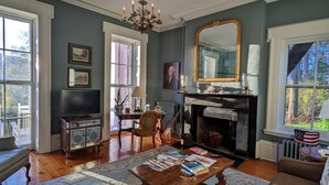 A living room with a fireplace, a television, and a large mirror. - Cromwell Manor Inn (Cornwall)