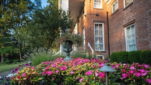 A garden with vibrant flowers and a decorative urn in the center, surrounded by a brick building with windows and a neatly trimmed hedge. - Cromwell Manor Inn (Cornwall)