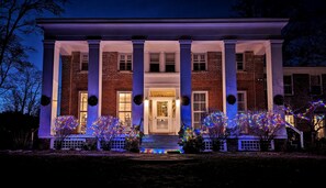 A two-story brick house with a front porch, columns, and a door with a wreath.