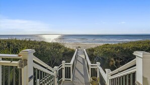A wooden staircase leading to a beach with a clear view of the ocean.