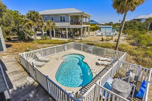 A pool area with a wooden deck, lounge chairs, and a small pool.