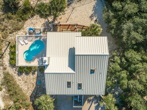 An aerial view of a modern house with a swimming pool, a deck, and a small garden area.