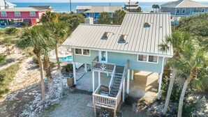 Una proprietà fronte spiaggia con una casa a due piani, un portico coperto e una piccola piscina.