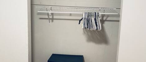 A closet with a hanging rod, a storage box, and a floor fan.
