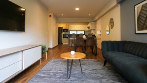 Ein modernes Wohnzimmer mit einer Couch, einem Couchtisch und einem an der Wand befestigten Fernseher.