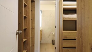 Ein schmaler Korridor mit Holzbögen auf beiden Seiten, der zu einem Badezimmer mit Marmorwand und Toilette führt.