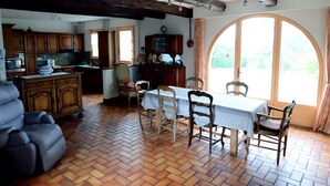 A dining area with a table and chairs, wooden cabinets, and a kitchen in the background. - Ty - Néhué (Crac'h)
