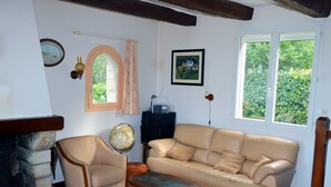 A living room with a leather sofa, armchair, and a coffee table. There's a fireplace, a globe, and a framed picture on the wall. - Ty - Néhué (Crac'h)