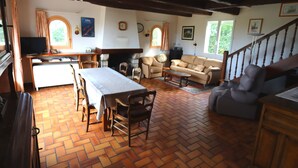 A spacious living area with a wooden floor, a dining table, a sofa, and a television. - Ty - Néhué (Crac'h)