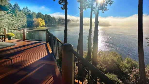 Une terrasse en bois surplombant un lac, avec vue sur les arbres et une atmosphère brumeuse.