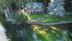 Une propriété située au bord d’un lac, comprenant une maison à deux étages, un quai et un mur en pierre.