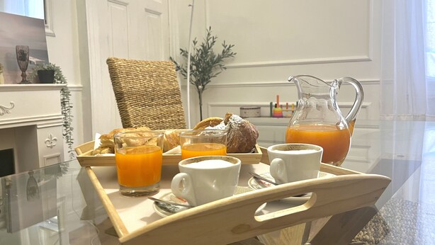 Een ontbijfwagen met croissants, sap en een karaf sinaasappelsap op een glazen tafel.