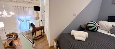 A bedroom with a bed, a wooden horse sculpture, a beach ball, and a glass shelf with a lamp.
