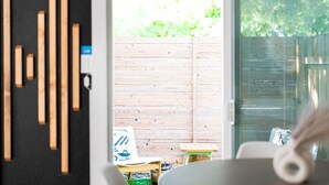 A modern room with a wooden wall, a sliding glass door leading to an outdoor area, and a small table with a chair.