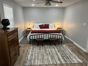 Ein Schlafzimmer mit einem Bett, Nachttischen, einer Kommode, einem Deckenventilator und einem Teppich.
