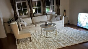 A living room with a white sofa, two small side tables, a white textured rug, and a wooden floor. - Amazing location.. walk to beach and restaurants.. all furnishings are brand new (Delray Beach)