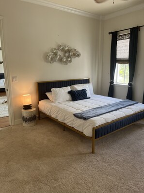 A bedroom with a bed, a bedside lamp, a decorative wall piece, and a window with curtains. - Amazing location.. walk to beach and restaurants.. all furnishings are brand new (Delray Beach)