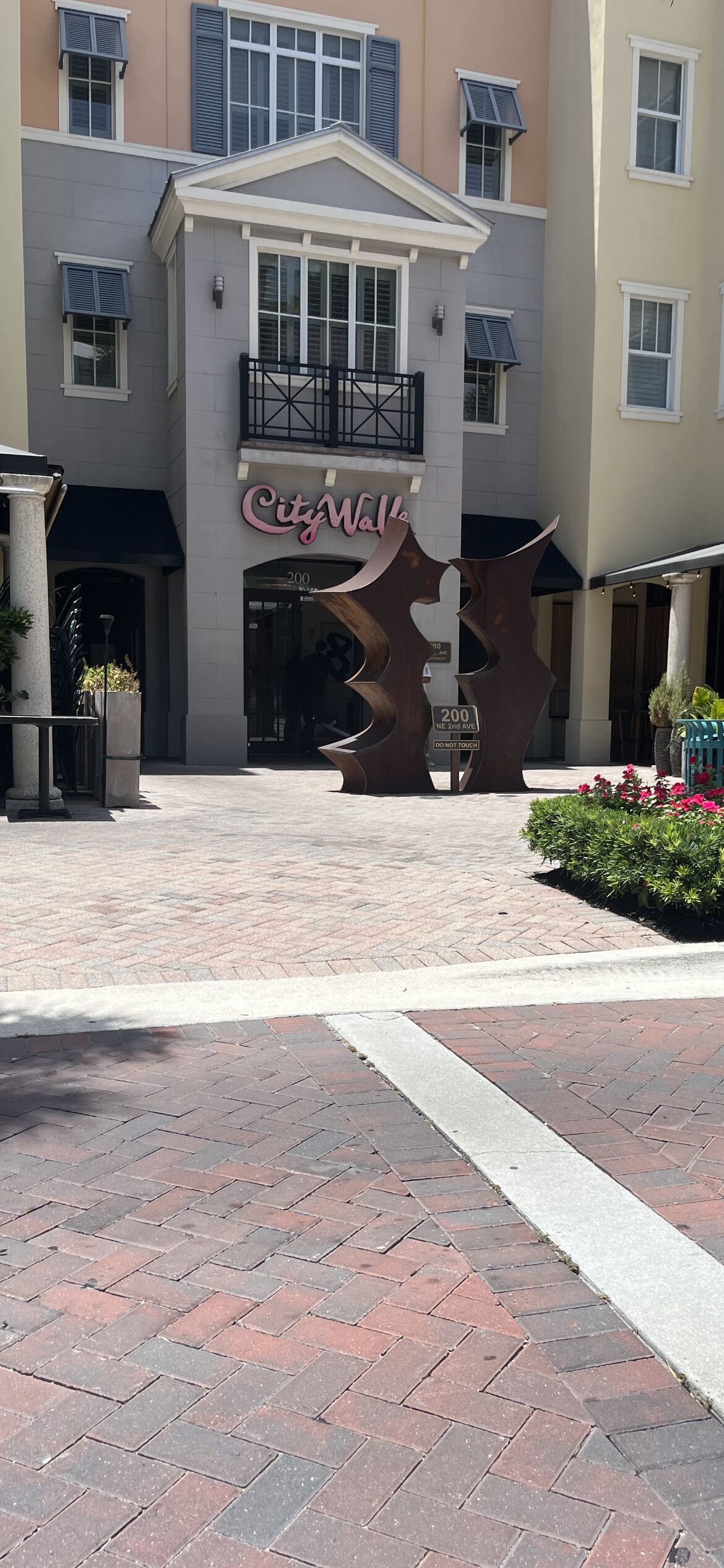 Un bâtiment sur lequel on peut voir une enseigne « CityWalk », une grande sculpture métallique et une entrée pavée de briques.
