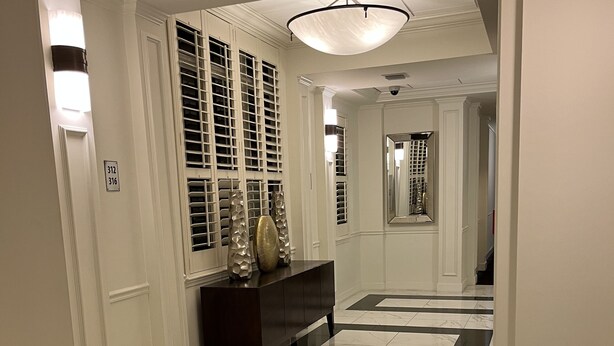 A hallway with marble flooring, a dark wooden bench, and a large mirror on the wall. - Amazing location.. walk to beach and restaurants.. all furnishings are brand new (Delray Beach)