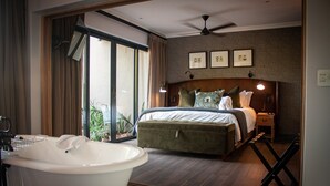 A bedroom with a large bed, a bedside table, a nightstand, a ceiling fan, and a view of the outdoors through a sliding door. - Kruger National Elephant Point Lodge (Mbombela)