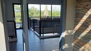 A covered outdoor patio with a seating area, a view of the surrounding greenery, and a stone wall on one side. - Kruger National Elephant Point Lodge (Mbombela)