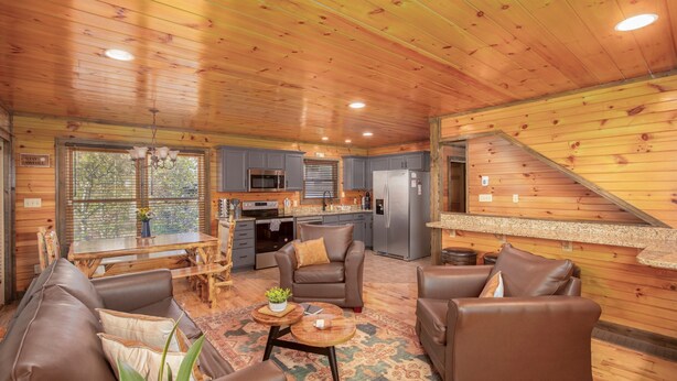 Un intérieur de chalet chaleureux comprenant un coin repas, des sièges, une cuisine et un escalier.