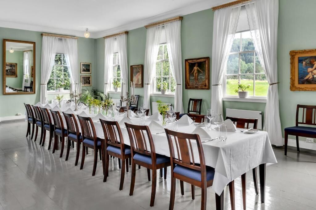 A dining room with a long table set for a meal, surrounded by chairs.