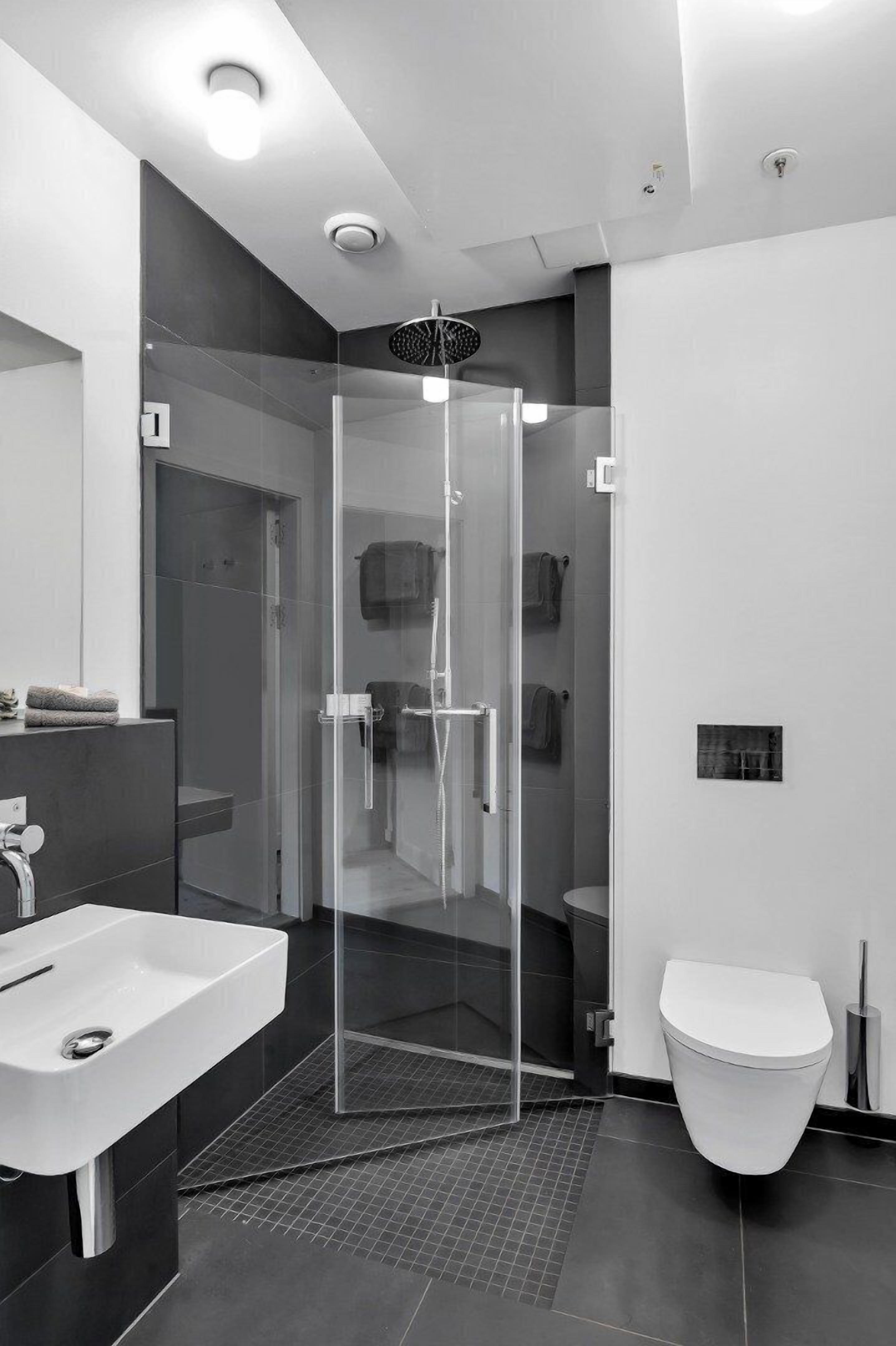 Ein modernes Badezimmer mit einer gläsernen Duschkabine, einem weißen Waschbecken und einer Toilette.