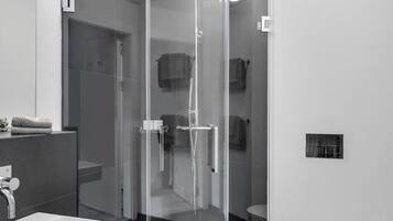 Ein modernes Badezimmer mit einer gläsernen Duschkabine, einem weißen Waschbecken und einer Toilette.