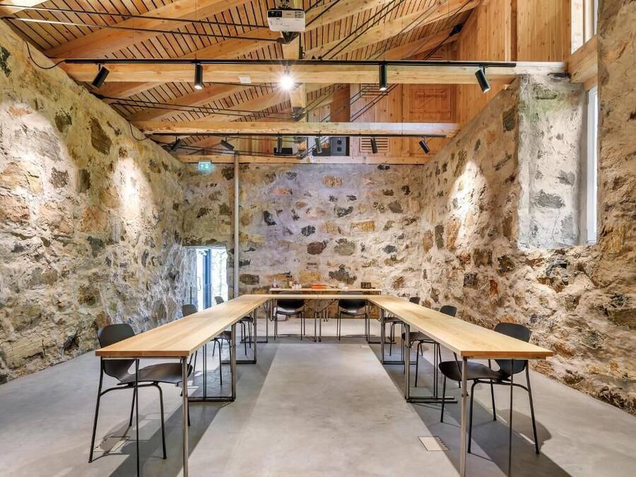 A conference room with a long table, chairs, and a stone wall backdrop.