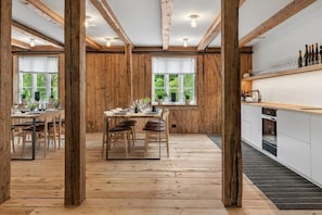 A rustic wooden interior with a dining area, kitchen, and large windows. - Boen Gard (Kristiansand)