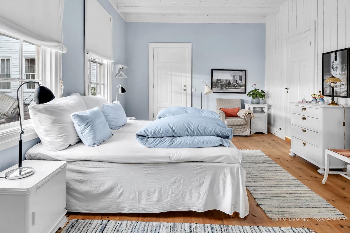 A bedroom with a bed, bedside tables, a chair, a dresser, and a door.