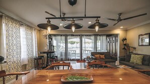 Un amplio salón con una gran mesa de madera para comer, un sofá y un ventilador de techo.