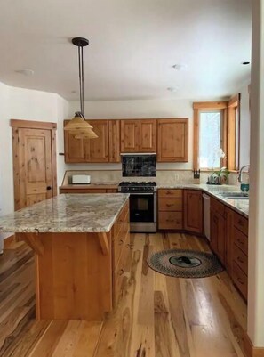 Enjoy cooking in this kitchen with a central island, wooden cabinetry, and a stainless steel stove.