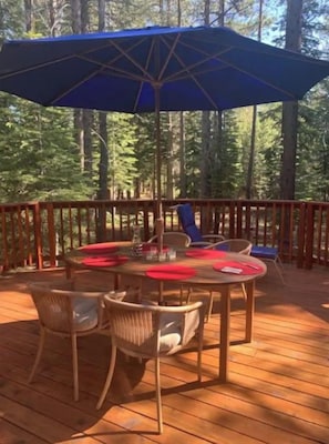 A wooden deck with a table and chairs, an umbrella, and a railing. - Daquino Tahoe Donner Retreat - Pet Friendly! (Truckee)