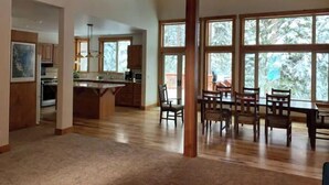 A spacious kitchen with a central island, wooden cabinets, and large windows offering a view of trees. - Daquino Tahoe Donner Retreat - Pet Friendly! (Truckee)
