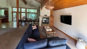 A spacious living room with a large sofa, a fireplace, and a television mounted on the wall. - Daquino Tahoe Donner Retreat - Pet Friendly! (Truckee)