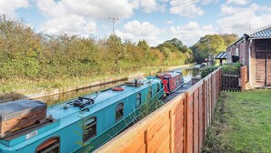 A narrow canal with a narrowboat docked alongside a wooden fence. - 5 bedroom accommodation in Heritage Marina, near Congleton (Heritage Marina, near Congleton)