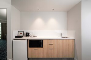 A compact kitchen with a built-in dishwasher, a coffee maker, and a sink. - The Sebel Twin Towns Coolangatta (Tweed Heads)