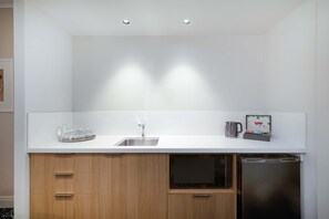 A modern kitchen with a white countertop, stainless steel sink, and a built-in dishwasher. - The Sebel Twin Towns Coolangatta (Tweed Heads)