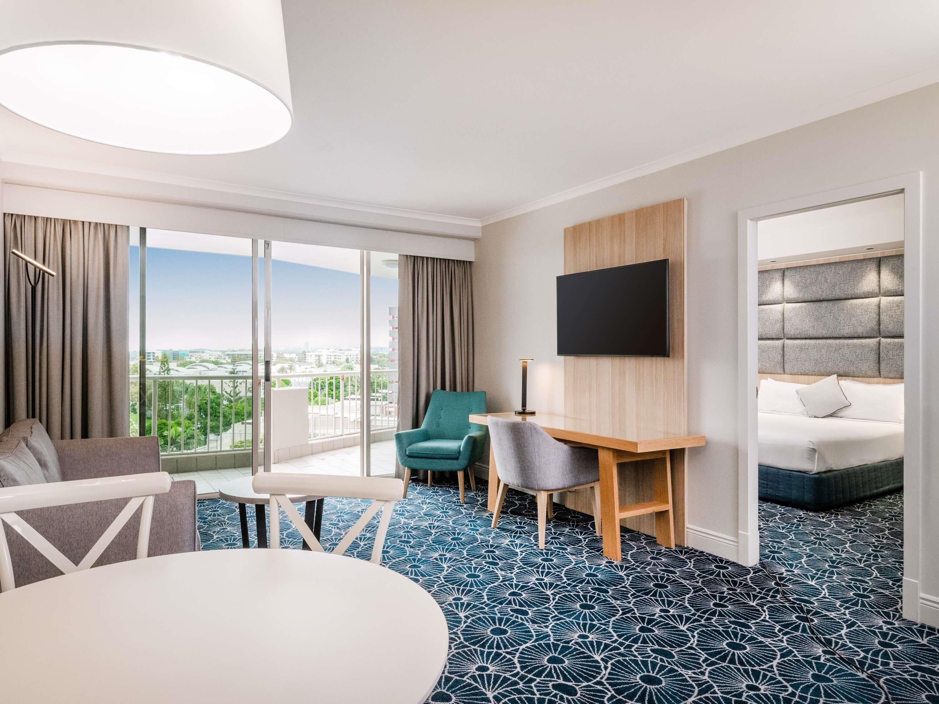 Ett hotellrum med ett stort fönster, en säng, ett skrivbord och en stol.