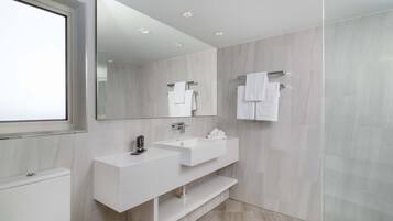 A modern bathroom with a large mirror, two sinks, and a shower area.